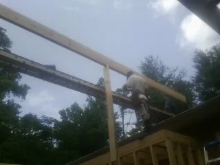 Carpenter setting a ridge beam over a new addition frame — Ice Dam Removal by Roofing Brothers in Kingsley