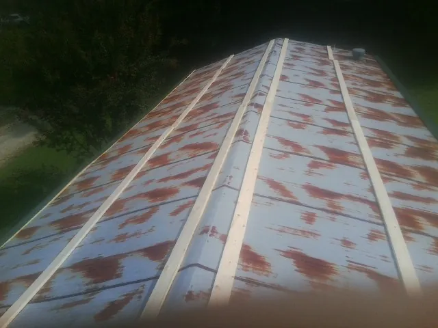 Rusted metal roof panels with new wood purlins before replacement — Storm Damage Roof Repair in Kingsley by Roofing Brothers