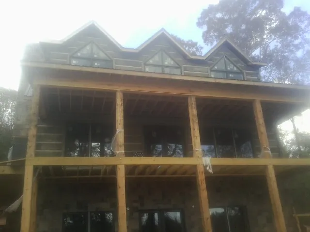 Dormers and porch framing on a large log home under construction — Roof Coating work by our crew in Kingsley