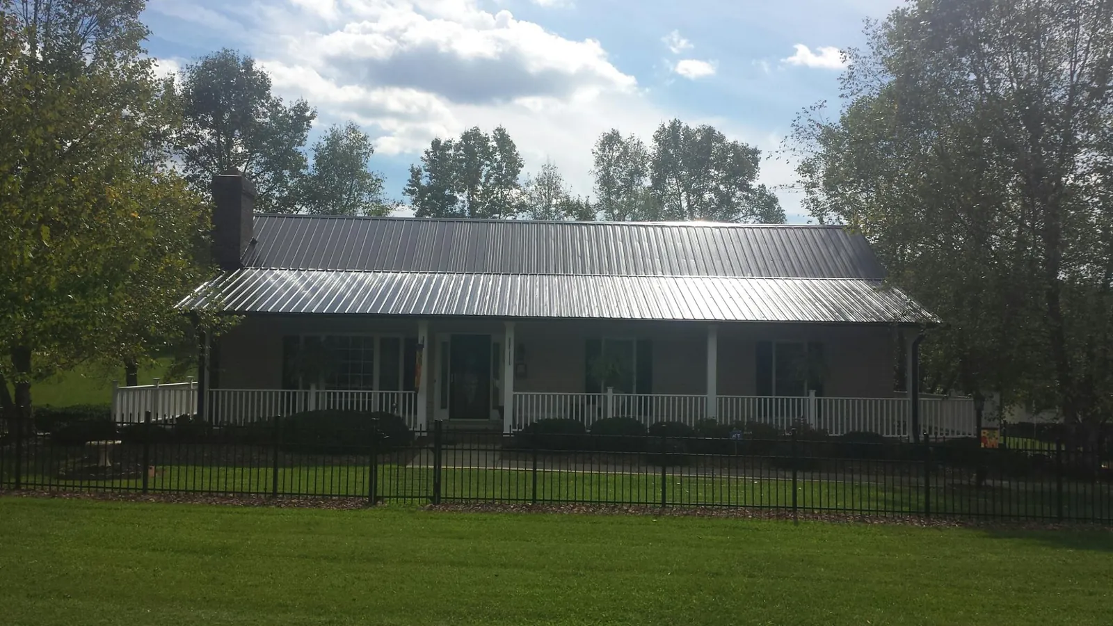Gray metal roof on a brick ranch with a full width front porch — Gutter Guard Installation work by our crew in Kingsley
