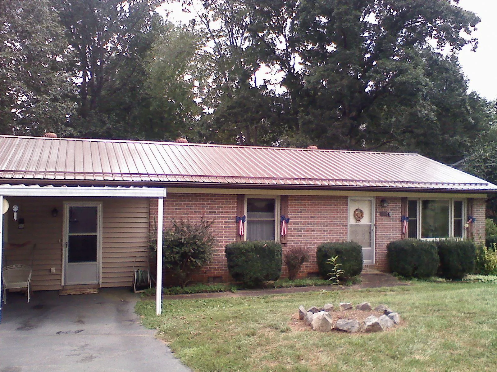 Bronze metal roof and carport on a brick ranch home — Roof Repair work by our crew in Kingsley