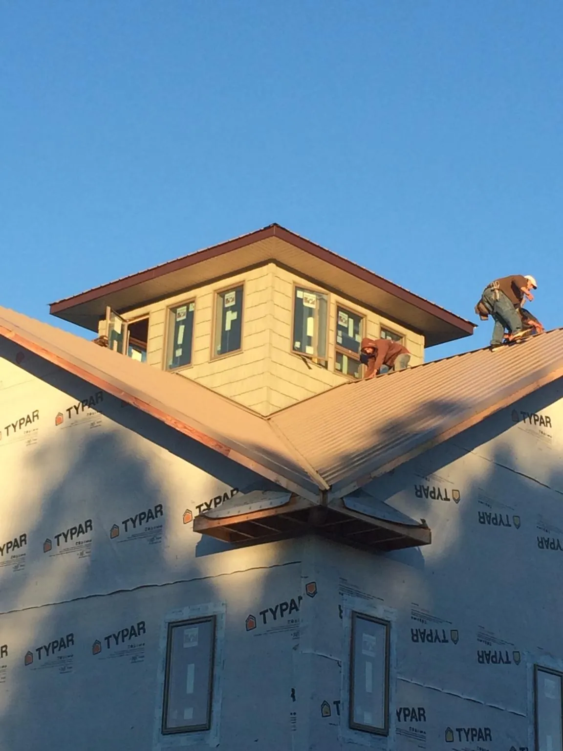 Roofers working around a rooftop cupola on a new metal roof at sunset — Roof Waterproofing in Kingsley by Roofing Brothers